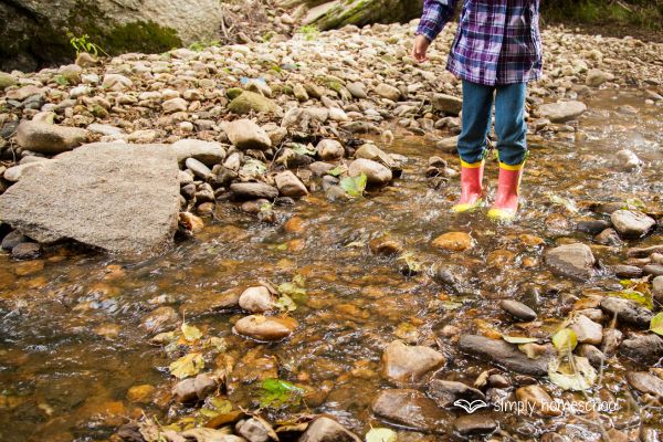 Boy in gumboots playing in a river: Advice for simplifying homeschooling from Simply Homeschool