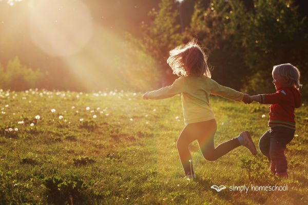 Two children running in a field at golden hour: Advice for simplifying homeschooling from Simply Homeschool